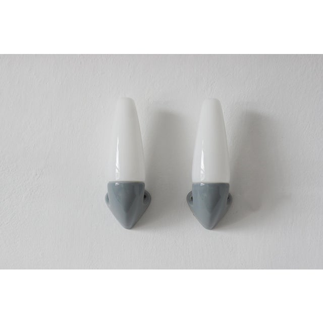 A pair of minimalist wall lamps, designed by Stig Carlsson for the Swedish manufacturer Ifö—a brand known for its top-...