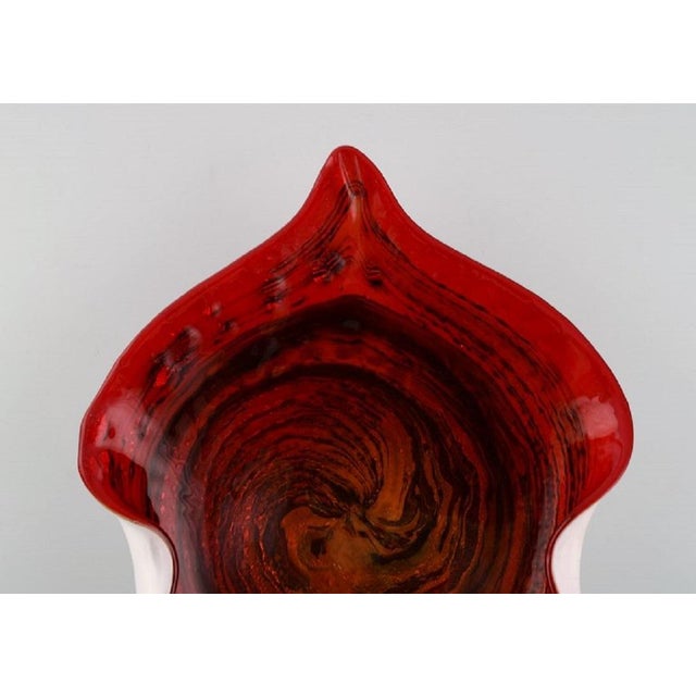Large leaf-shaped Murano bowl in mouth-blown art glass with wavy edges. Red shades. Italian design, 1960s. Measures: 28.5...