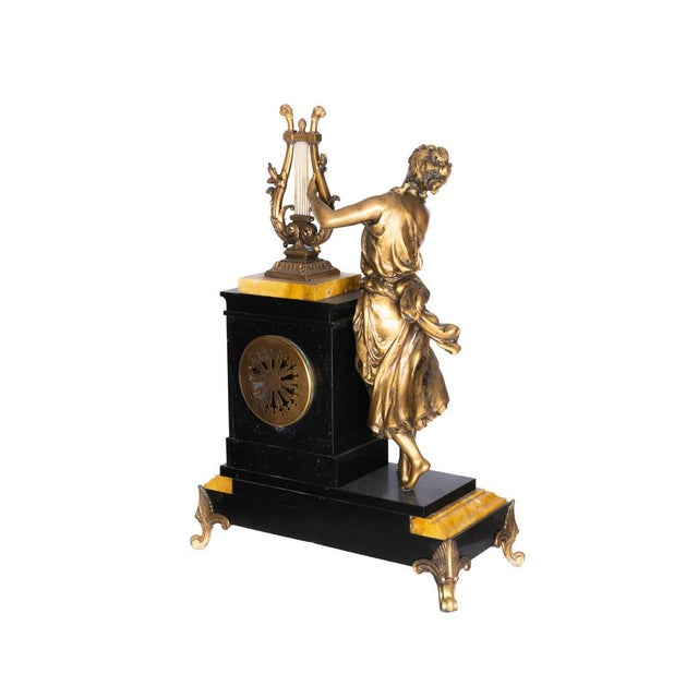 A French mantel clock from the early 20th century (c.1905–1920), featuring a bronze sculpture of a lady playing a harp...