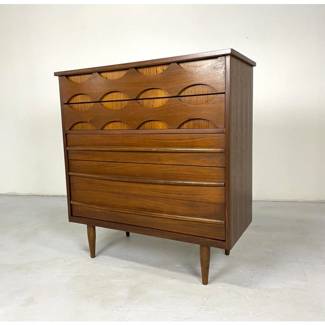 A stunning and rare sculptural highboy dresser by United with beautiful carved eye-shaped drawers. There are four drawers...