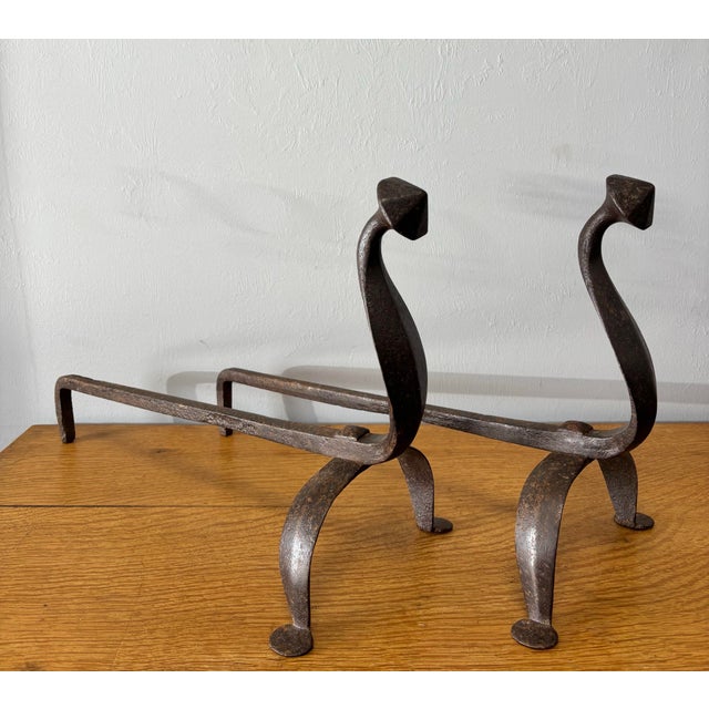 This striking pair of early 20th-century wrought iron andirons brings a sense of drama and restraint to the hearth—objects...