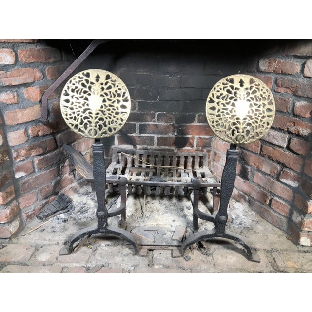 A pair of large antique English brass and iron fireplace andirons with decorative circular medallion tops with ornate...