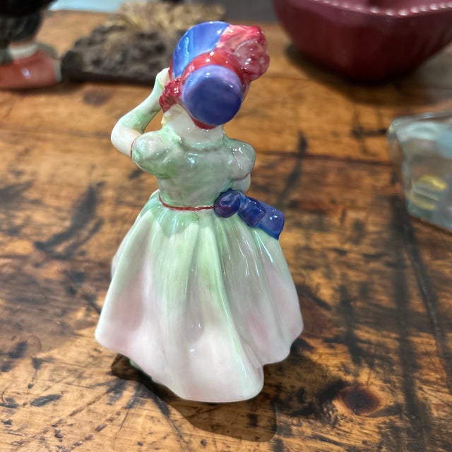 This sweet little figure is in a green and blue color way and was designed by leading Royal Doulton artist Leslie...