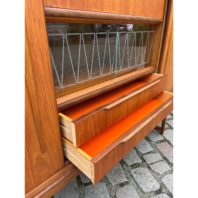 This mid-century highboard offers space and style for your home! In addition to a display cabinet and drawers, it also...