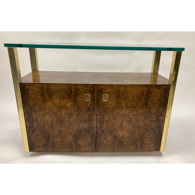 A striking mid-century modern bar cart or dry bar, featuring an exquisite bookmatched burl veneer façade that creates a...