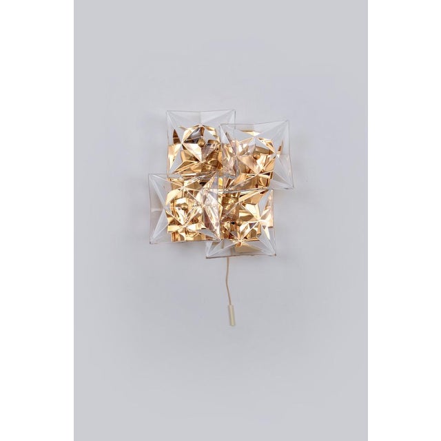 A wall lamp with crystal glasses, made by kinkeldey, germany, circa 1970-1979. it is composed of square pieces of crystal...