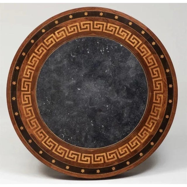 The circular table with contrasting marquetry of star decoration on the outer rim and then stylized greek key below it...