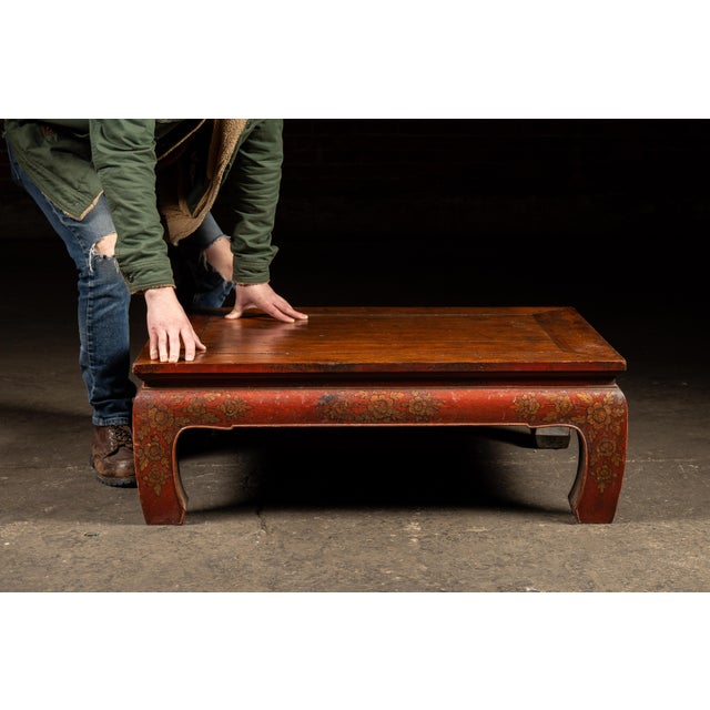 Low lacquered altar or tea table with floral gilt detailing. This handcrafted table features a paneled hardwood top above...