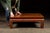 Low lacquered altar or tea table with floral gilt detailing. This handcrafted table features a paneled hardwood top above...