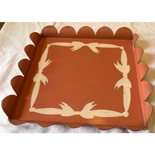 Charming vintage metal tray with a scalloped edge and a hand painted cream bow border. The tray is terracotta pink color...