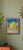 A vibrant, whimsical cityscape rendered in a lively, expressive palette of brilliant blue, sunny yellow, soft pink, and...