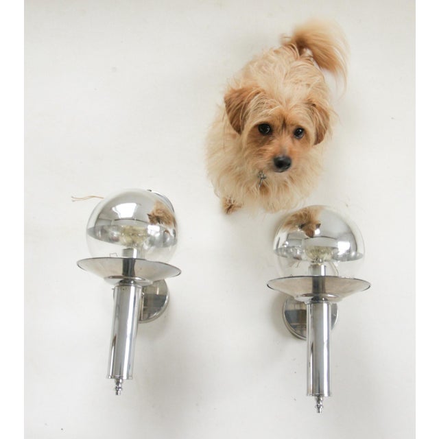 Elegant pair of Dutch mid-century wall sconces in polished chrome with mirrored, half-silvered glass globe shades. Each...