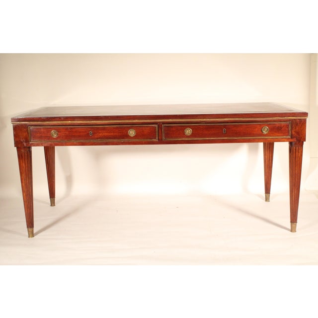 Louis XVI style brass mounted mahogany desk with tooled leather top, circa 1980. With an inset tooled leather top and...