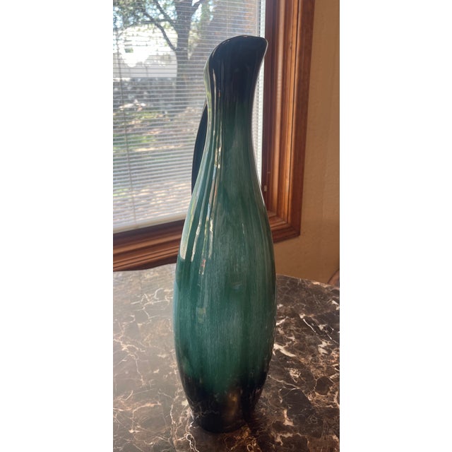 Tall peacock blue and black glazed pottery pitcher with sleek black handle. Spout has a 3 inch opening. Artist marking.