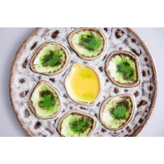 A vibrant Mid-Century French green and yellow majolica oyster plate in the Vallauris style, six wells with a lemon center.