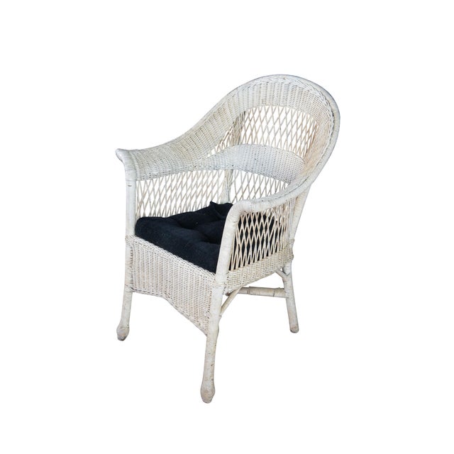 Antique woven wicker / rattan arm chair featuring a reticulated fan back design with flared arms and skirted front....