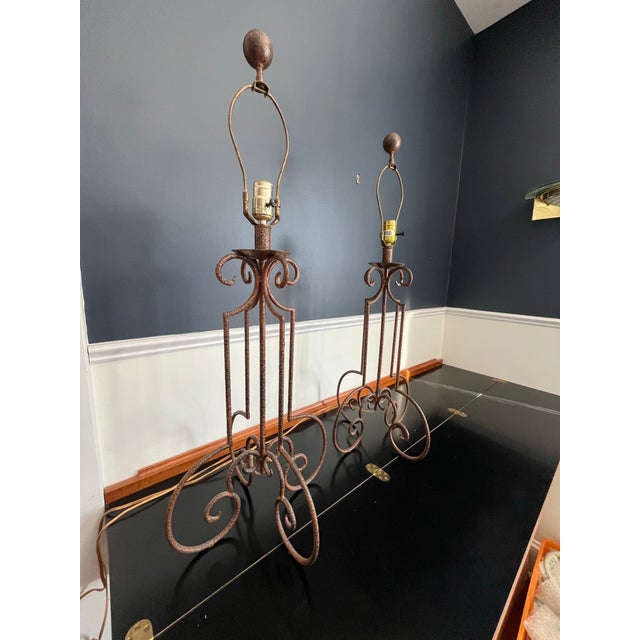An evocative pair of Spanish Revival–style wrought iron table lamps showcasing hand-forged scrollwork and a richly aged...