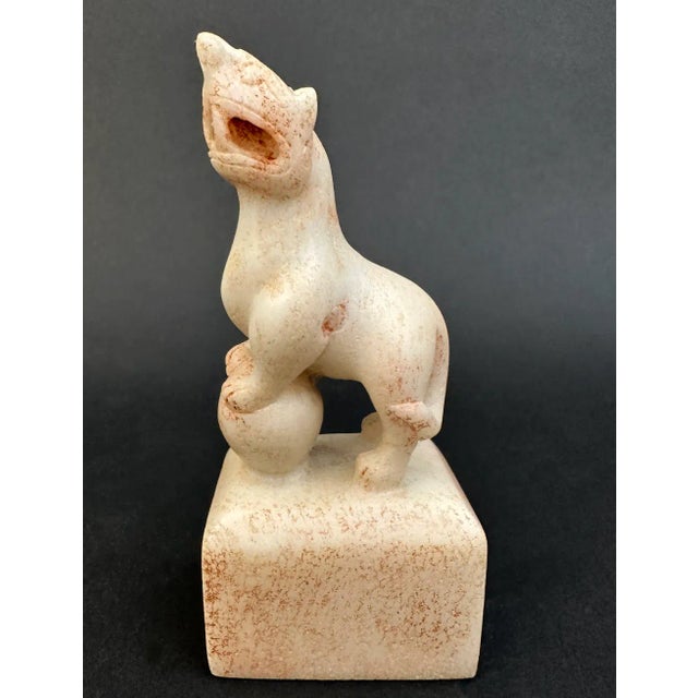 A Jade Foo dog, its front paws mounted on a ball, its mouth held open in a snarl. A Foo dog, in Chinese culture, is a...