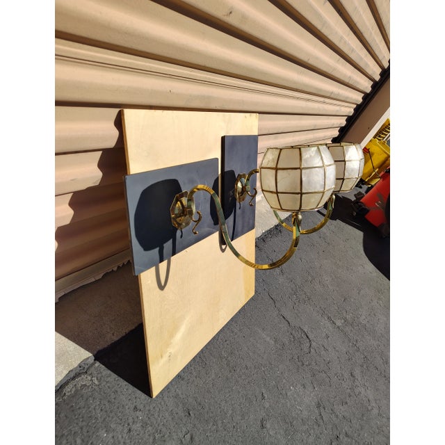 A vintage pair of brass and wood capiz shell wall lights mounted wooden back wall plate for stability anchoring the...