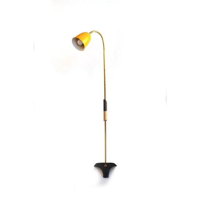 The 1950s floor lamp with a brass stem, black painted base, and a yellow spot shade exudes a vintage charm. The...