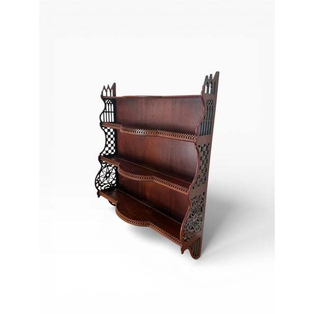 A beautifully detailed mahogany wall-mounted étagère featuring intricate Gothic-inspired fretwork and elegant Chippendale...