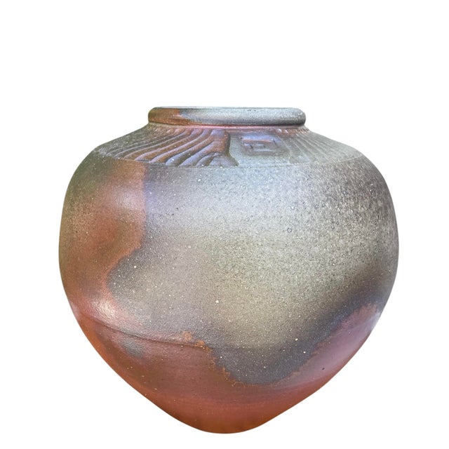 Large vintage studio pottery vessel featuring a rounded sculptural form with carved collar detailing and richly varied...