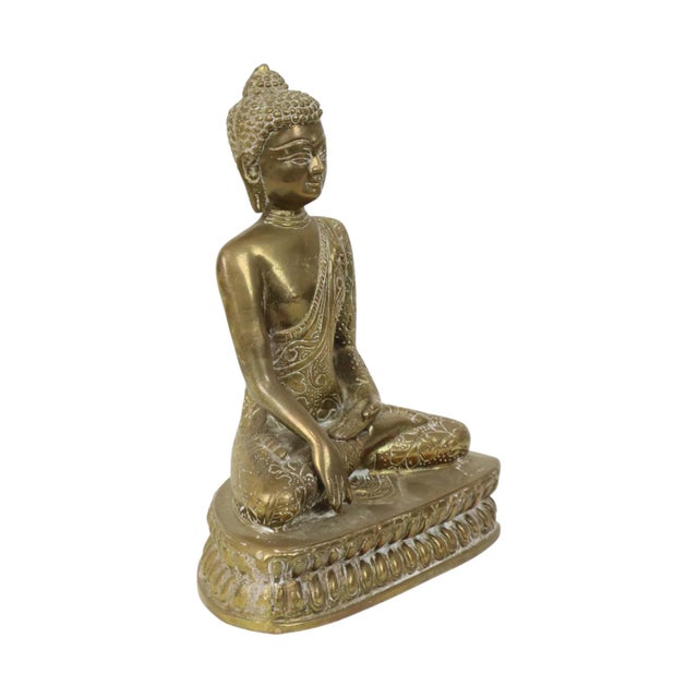 Vintage brass Buddha statue; the robe is richly decorated with detailed patterns. The Buddha sits on an ornate triangular...