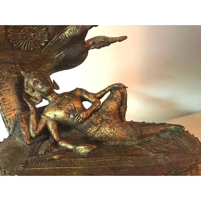 Depicting Buddha in his royal attires resting on a throne made of coiled naga body and sheltered by the canopy of the...