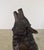 A dramatic and highly expressive bronze sculpture of a howling wolf, captured in a powerful upward stance. Seated with its...