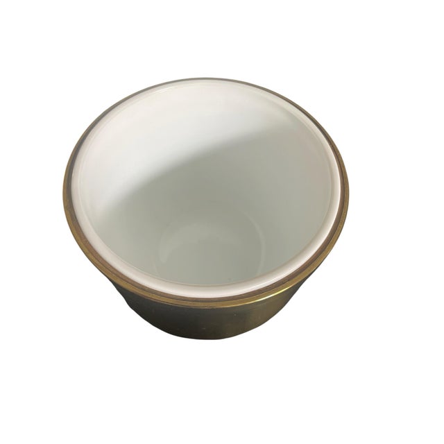 Chic Hollywood Regency style brass ice bucket . The ice bucket features a solid brass shell and top, with a milk glass...