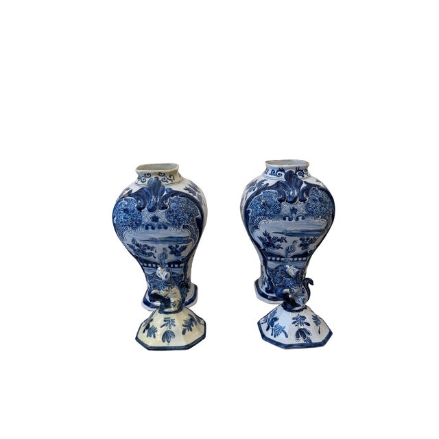 A charming pair of Dutch Delft-style covered urns, hand-painted in cobalt blue on a white glazed ground. The classic...