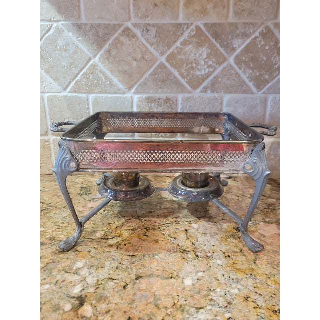 Vintage silver-plated footed double chafing dish frame featuring two fuel holders for sterno cans. It has beautiful ornate...