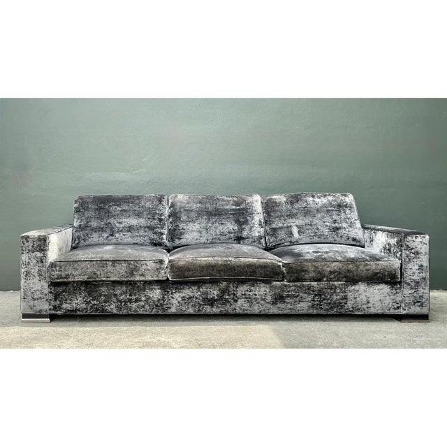 This monumental sofa commands attention through its expansive scale and richly textured crushed velvet upholstery, its...