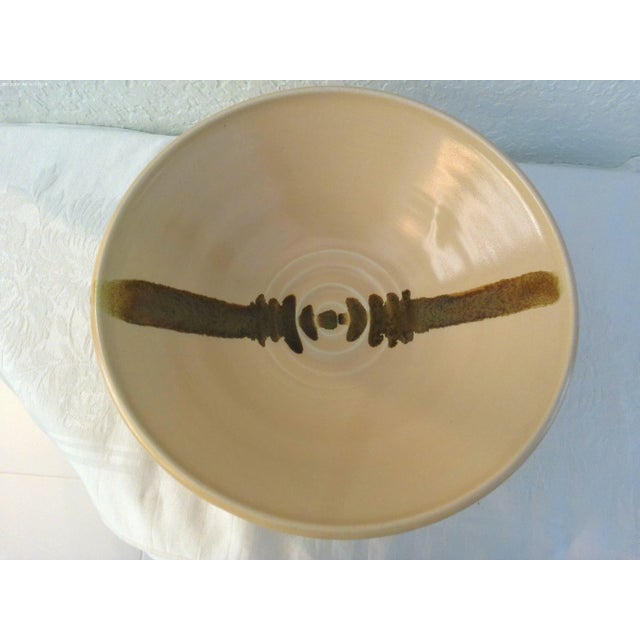 1990s Southwestern, generous size footed pottery bowl in pale pink featuring a brown abstract design across interior of...