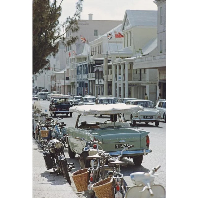 Bermuda Street Scene 1967 by Slim Aarons Slim Aarons Limited Estate Edition Bicycles, motorcycles, and cars on a street in...