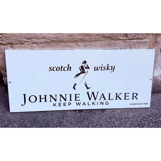 Original Johnnie Walker decorative sign, made on hardboard with a white background and black lettering. It features the...
