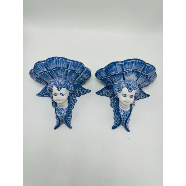These pieces are a pair of ornate ceramic wall sconces or decorative wall plaques. Here’s a detailed description: • Design...