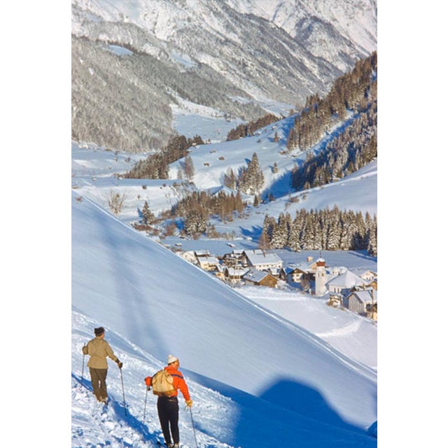 An Alpine Valley In Winter by Toni Frissell Two skiers look down into the valley at the St. Anton ski resort, Austria,...