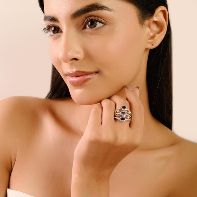 This elegant ring is crafted in 14K white gold, showcasing a 1-carat oval-cut blue sapphire as the centerpiece. The...