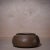 This vintage textured brown earthenware pottery bowl is a wide, shallow vessel with a rounded, bulbous shape. Its dark...