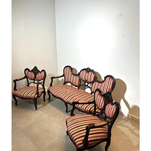 This elegant Victorian-style salon set features a beautifully carved dark wooden frame paired with rich red-and-gold...