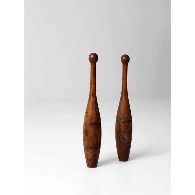 A striking pair of vintage Indian juggling pins, also known as wood meels, crafted from carved wood and rich with time-...
