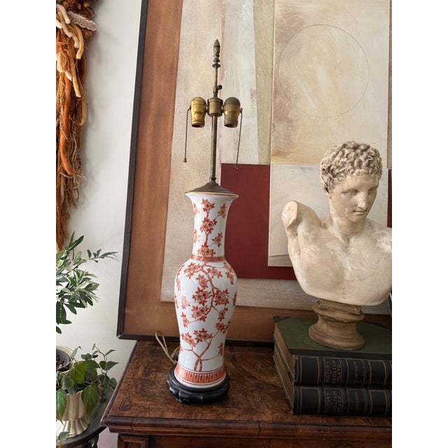 An elegant vintage chinoiserie table lamp featuring a warm cinnamon and white palette with delicate peach and gold...