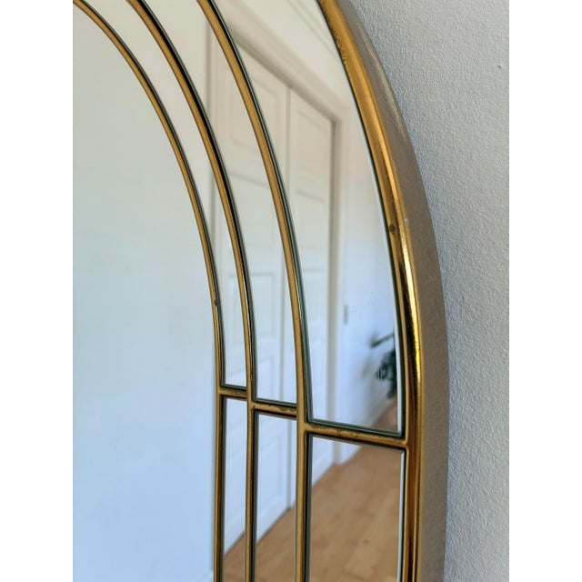 This vintage Belgian mirror dates from the 1980s and features an elegant arched shape with a gold-toned frame. The mirror...