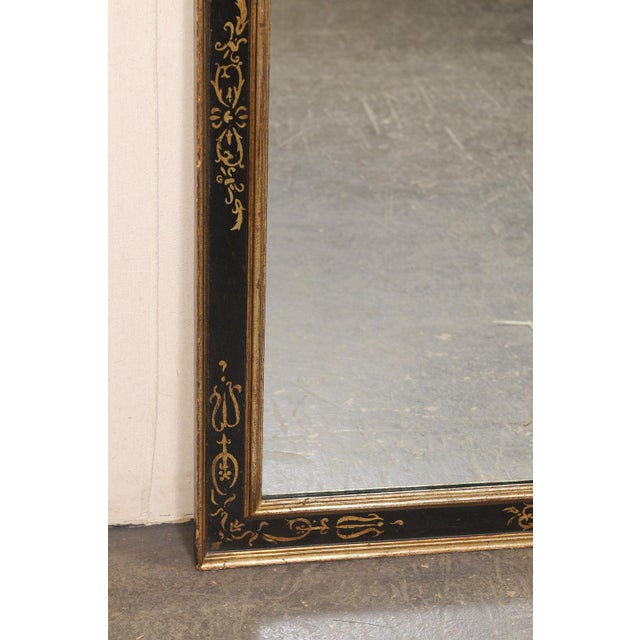 An Italian black and gilt decorated wall mirror. This elegant vintage wall mirror from Italy features a classic...
