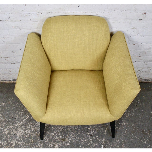 This is a pair of mid-century armchairs. They feature a subtle yellow fabric along with understated black lacquered legs....
