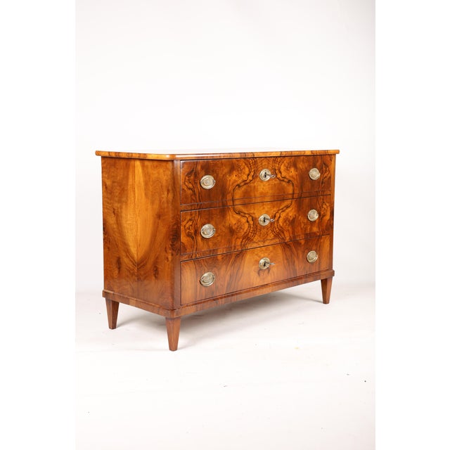 A very elegant Biedermeier chest of drawers in walnut burl veneer, with a beautiful grain pattern. The top features...