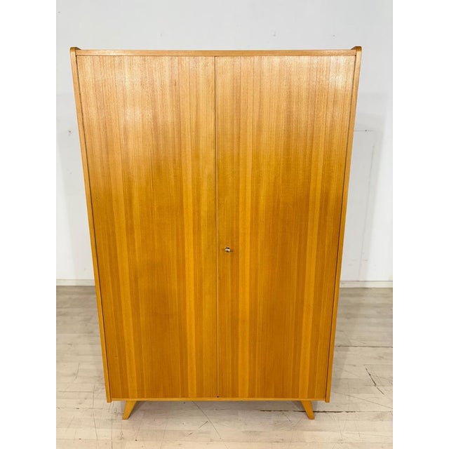 For sale is this beautiful, two-door wardrobe made of light wood with slightly splayed legs, as seen in the attached...