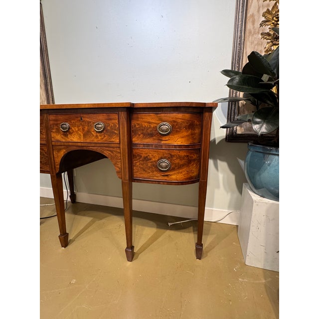 This is a 19th Century English mahogany sideboard. Its design was inspired by the Hepplewhite sideboards from the Regency...