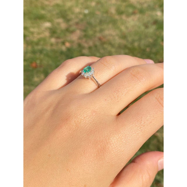 The 89th Avenue: Natural Emerald and Diamond Halo Ring in White Gold. The ring centers on a charming oval brilliant cut...